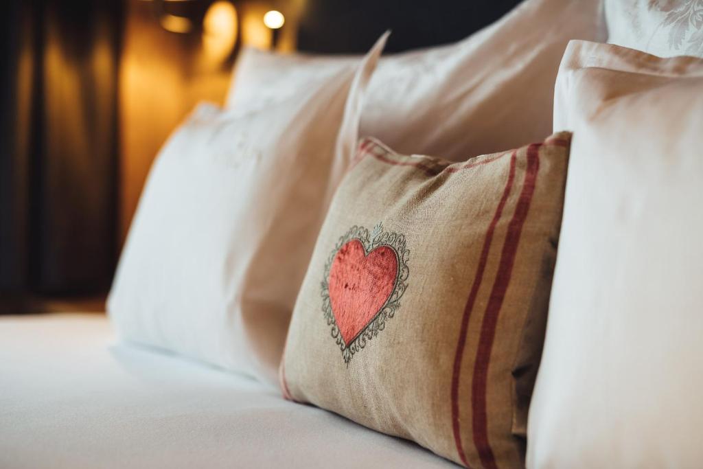 un cuscino rosso a cuore su un letto con cuscini bianchi di Schneeweiss lifestyle - Apartments - Living a Serfaus