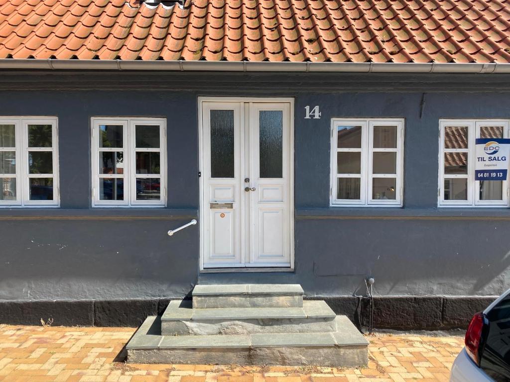 une maison bleue avec une porte blanche et des escaliers dans l'établissement byhus centralt i bogense, à Bogense