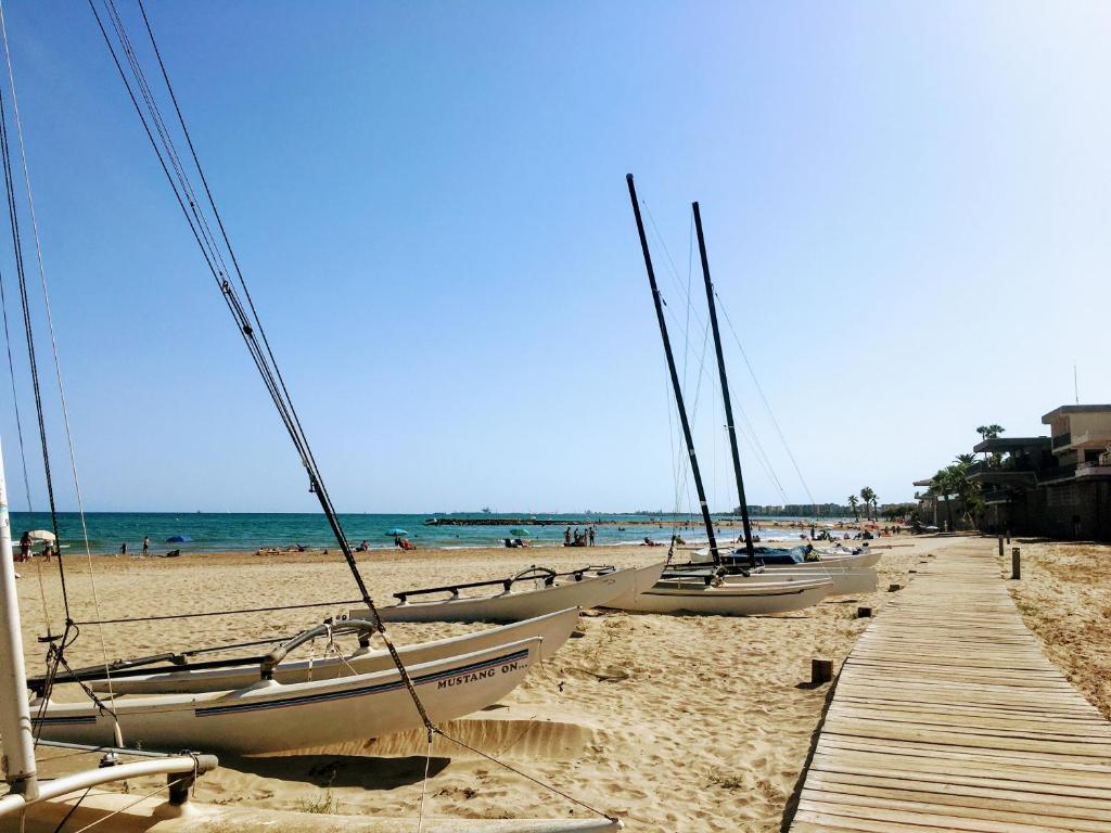 a row of boats on a beach with a dock at Piso vacacional con piscina en Benicassim in Benicàssim