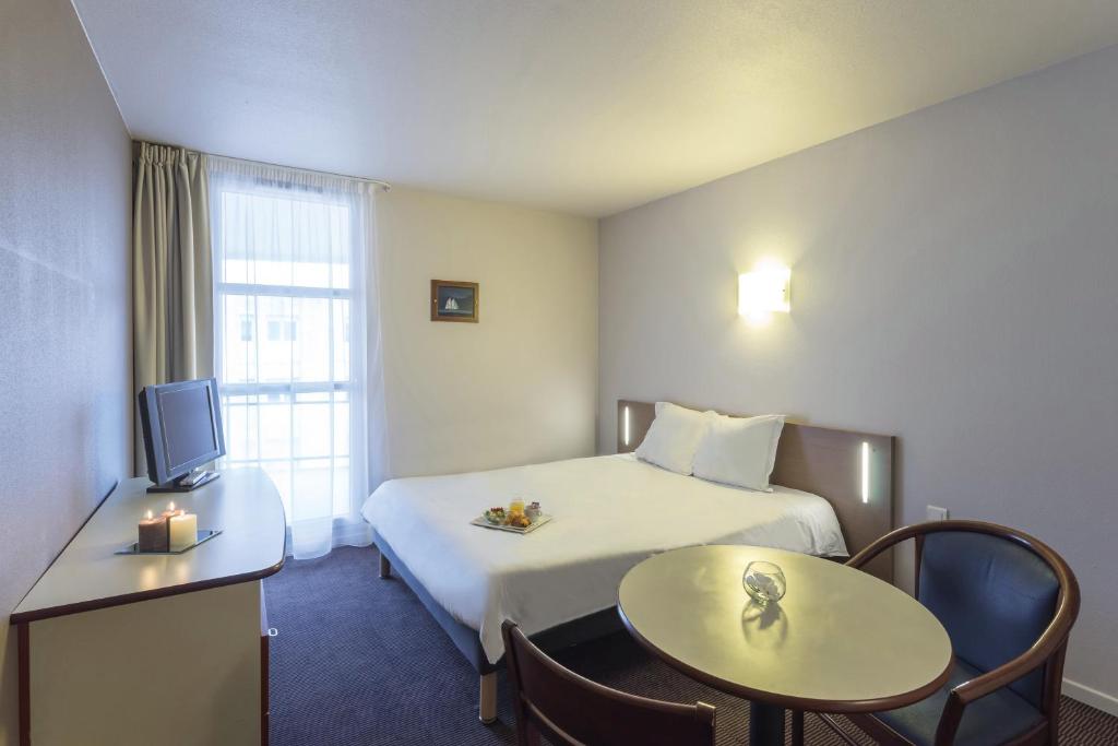 a hotel room with a bed and a table and a tv at Appart'City Classic Nancy in Nancy
