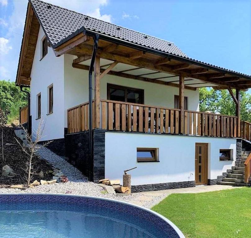 una casa con terraza junto a una piscina en Chata Nechata, en Velhartice