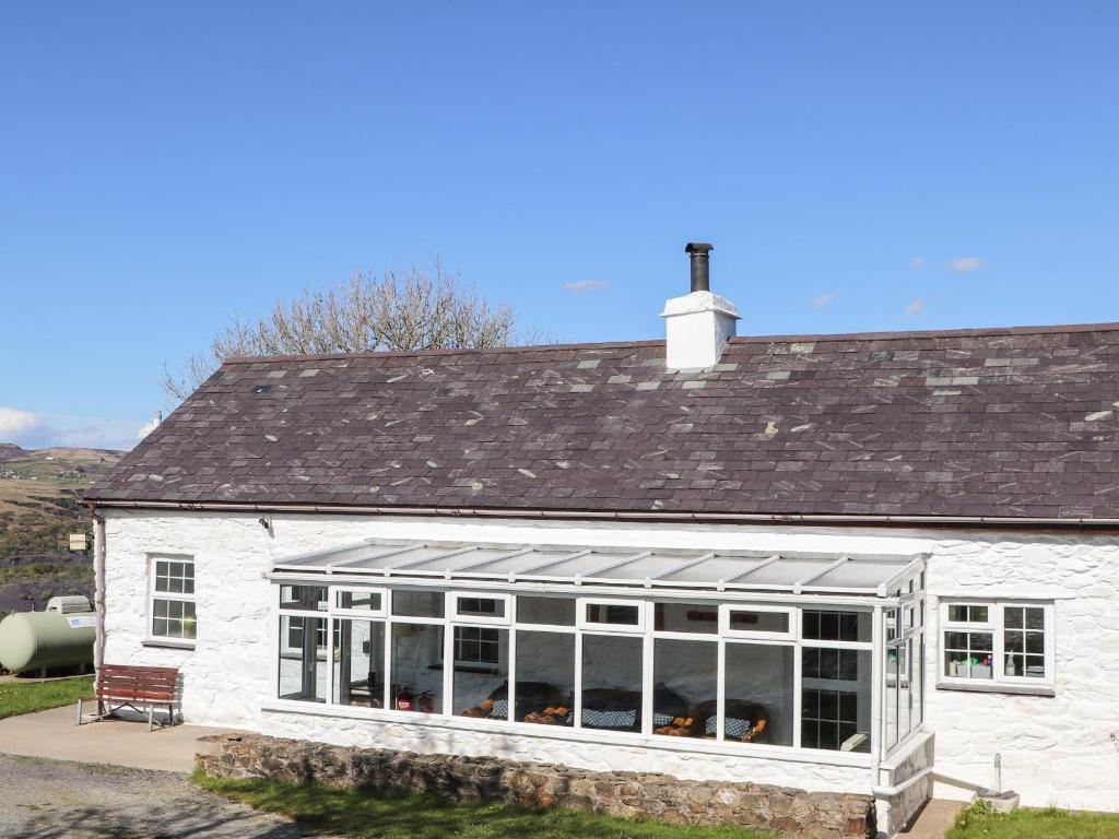 a white house with a conservatory with a roof at Fron Oleu in Caernarfon