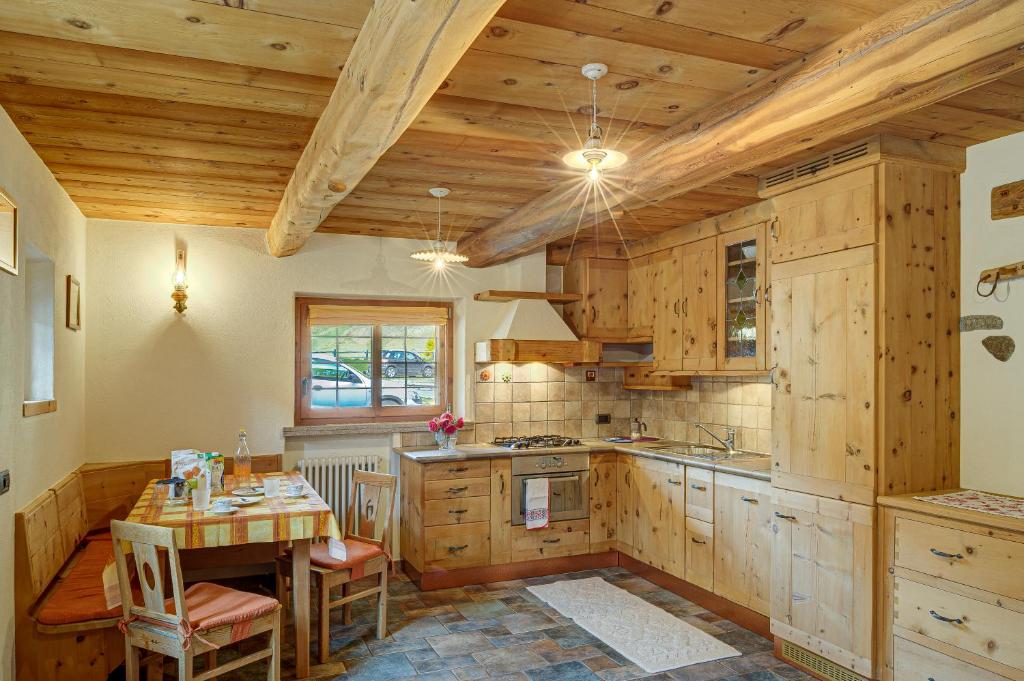kuchnia z drewnianymi szafkami i stołem z krzesłami w obiekcie Chalet Canton w Livigno