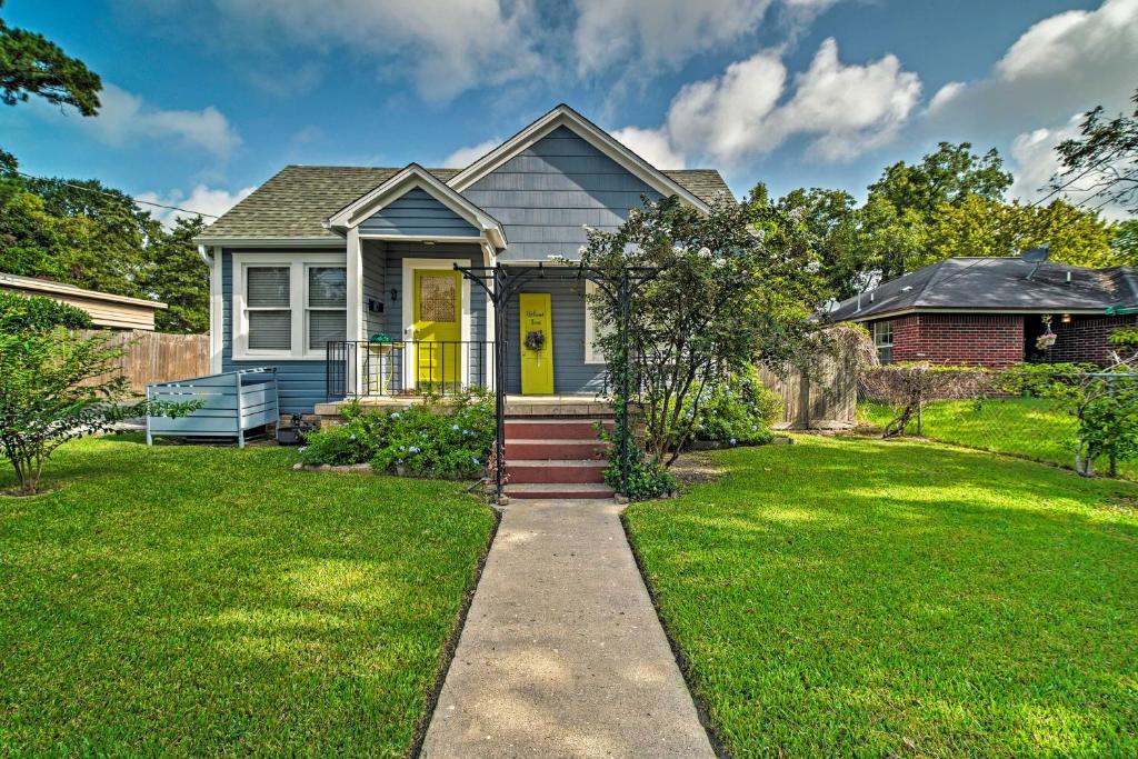 a house with a yellow door and a grass yard at Cozy Brenham Cottage with Private Patio and Yard! in Brenham