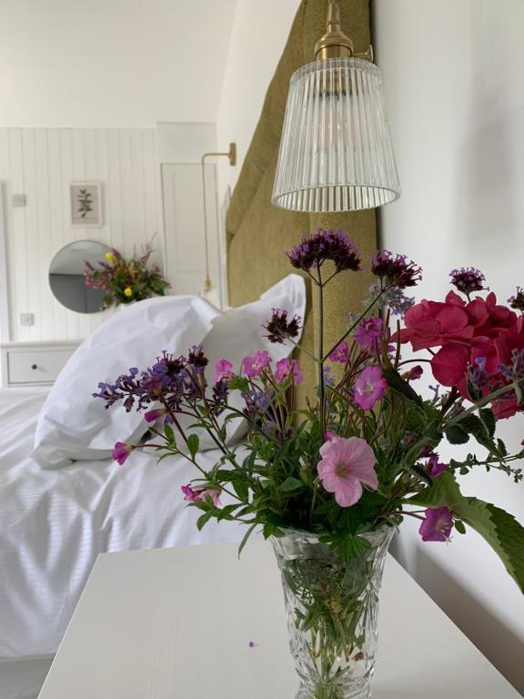 un jarrón de flores sentado en una mesa con una lámpara en Garden Cottage on Tintern Trails en Fethard on Sea