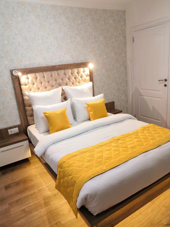 a bedroom with a large bed with yellow pillows at ONYX - Utopia Aparthotel in Braşov