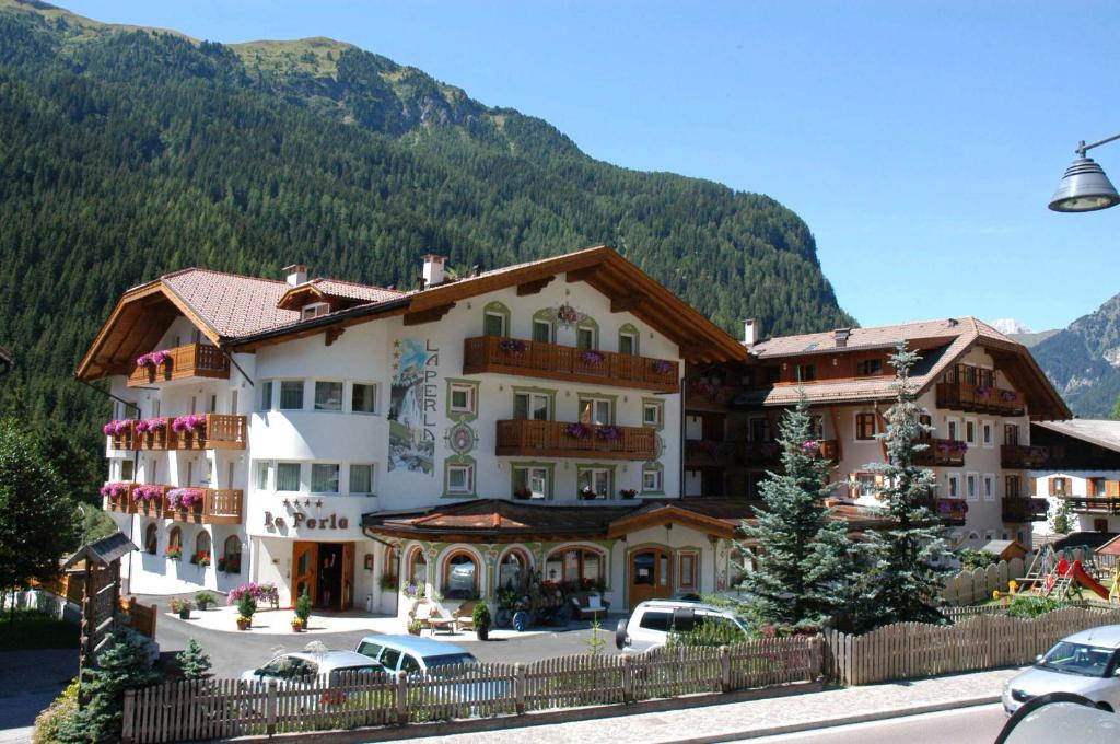 ein großes Gebäude vor einem Berg in der Unterkunft Hotel La Perla in Canazei