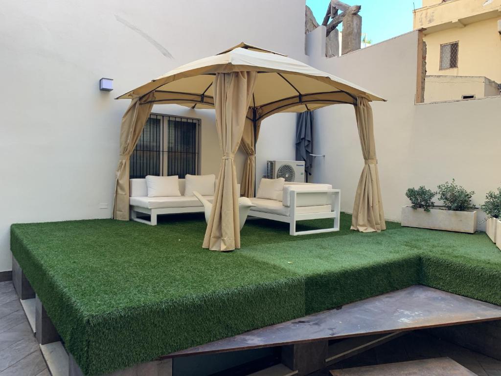 a gazebo with two couches and a green lawn at Neko Boutique Hotel in Cagliari