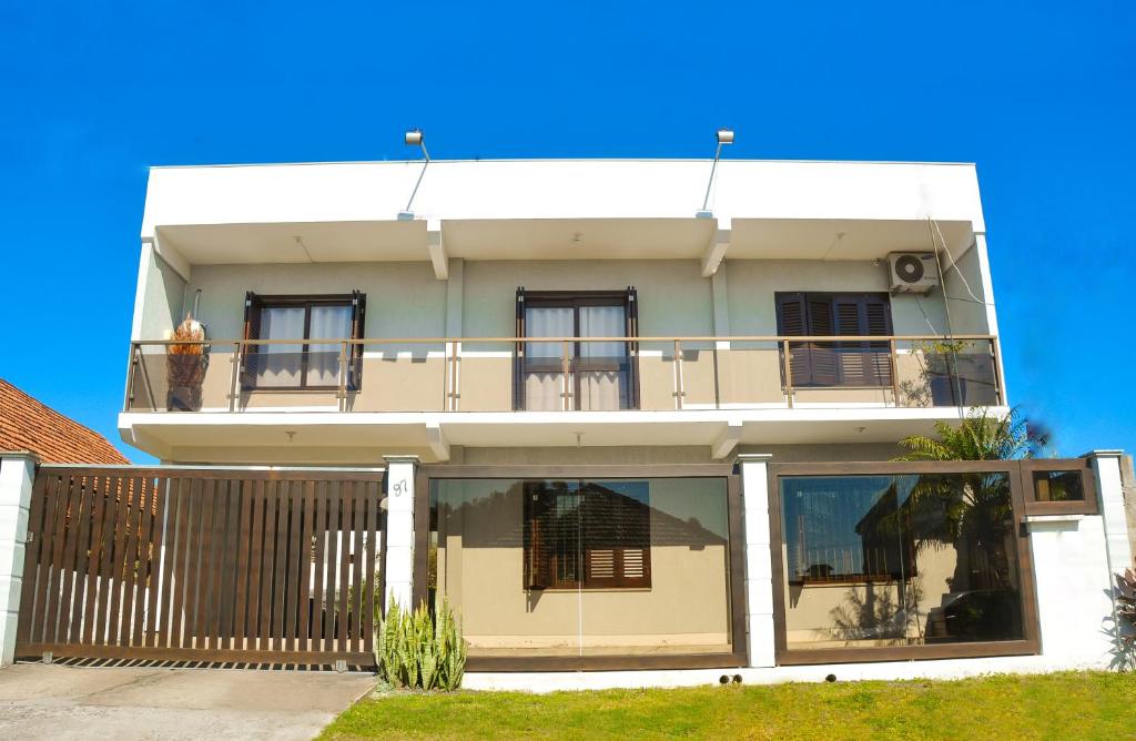 a white building with windows and a balcony at Classe Pousada in Imbé