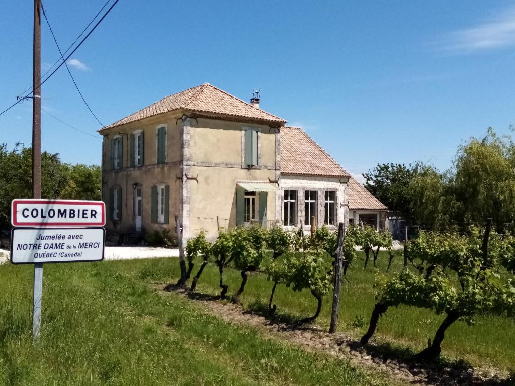 una casa con un cartel frente a un viñedo en Ancienne école de Colombier, en Colombier