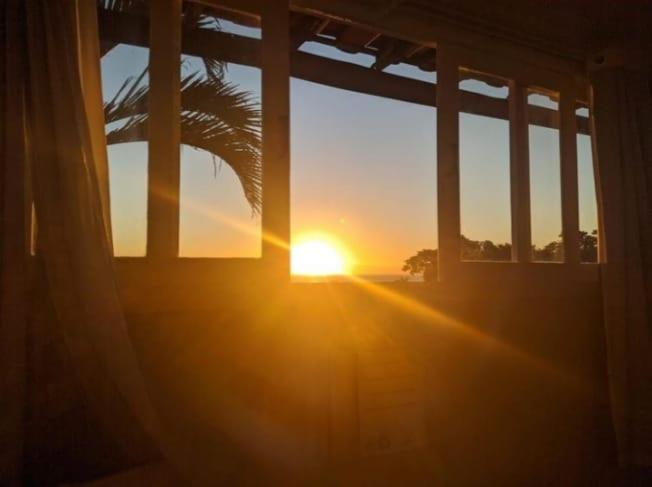een zonsondergang door het raam van een huis bij Pousada Areias Brancas in Búzios