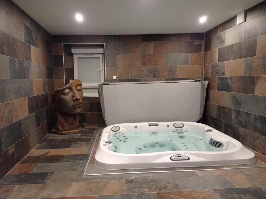 a jacuzzi tub in a bathroom with a statue at L'espaco in Saint-Jeure-dʼAy
