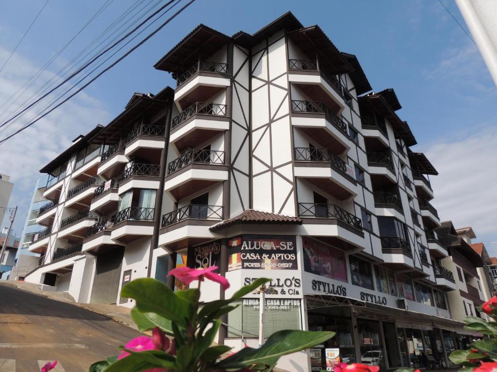 un edificio alto y blanco con balcones. en Apartamentos Morada do Sol, en Piratuba
