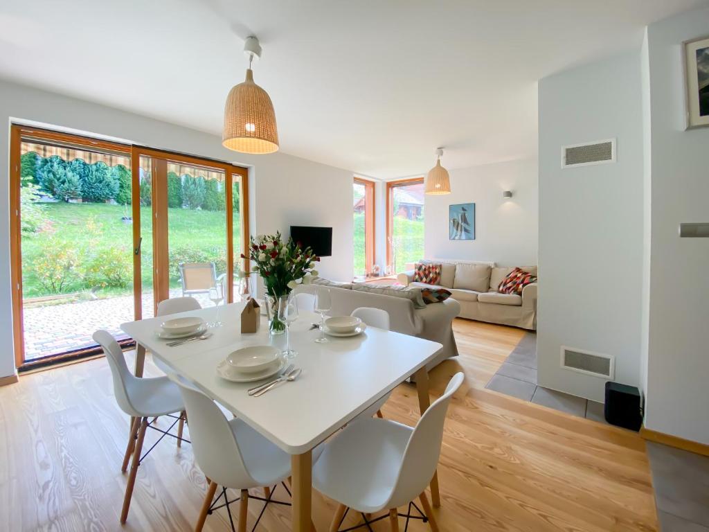 een eetkamer en een woonkamer met een witte tafel en stoelen bij Apartament Sielankowy z tarasem i grillem - Dream Apart in Ustroń