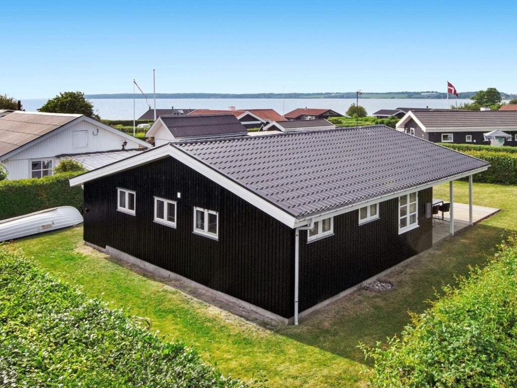 a black house with white windows in a yard at Holiday home Juelsminde LIX in Sønderby