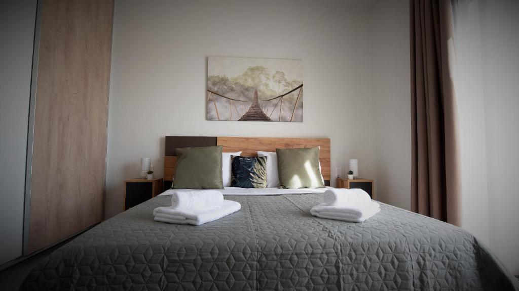 LUXURY AUTONOMOUS GROUND FLOOR APARTMENT في إيغومينيتسا: غرفة نوم عليها سرير وفوط