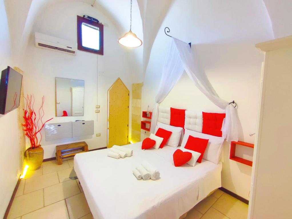 1 dormitorio con cama blanca y almohadas rojas en La Dimora della nonna Rosina, en Galatone