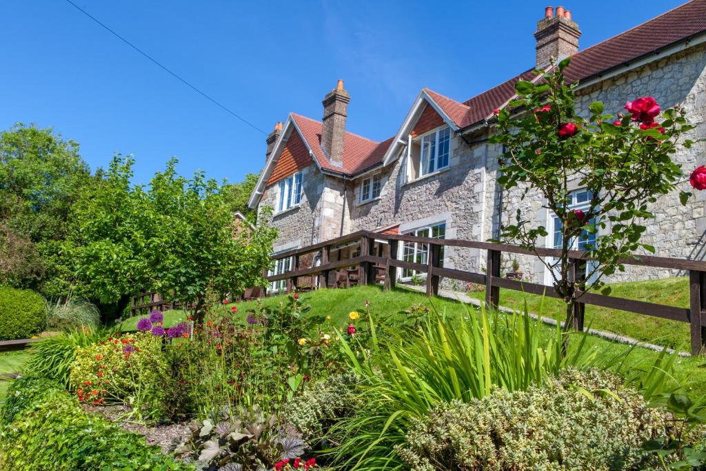 una antigua casa de piedra con un jardín delante de ella en Limestone Hotel, en Lulworth Cove