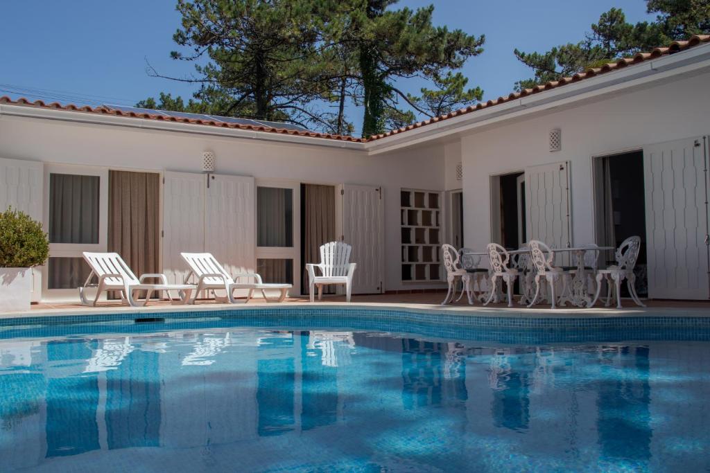 a swimming pool with chairs and a table at Ofir Beach House Bonança in Esposende