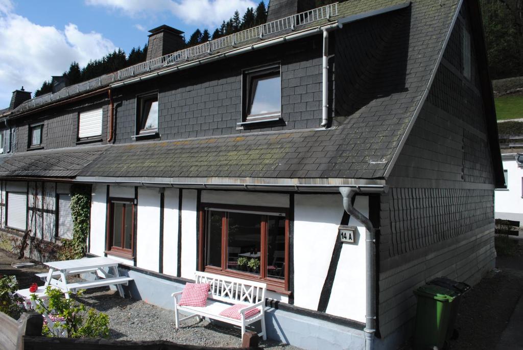 a black and white house with a bench in front of it at Vakantiehuis Ramsbeck in Ramsbeck