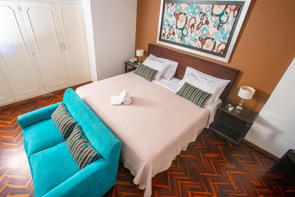 - une chambre avec un grand lit et un canapé bleu dans l'établissement Posada Blanca Hotel Boutique, à Piura