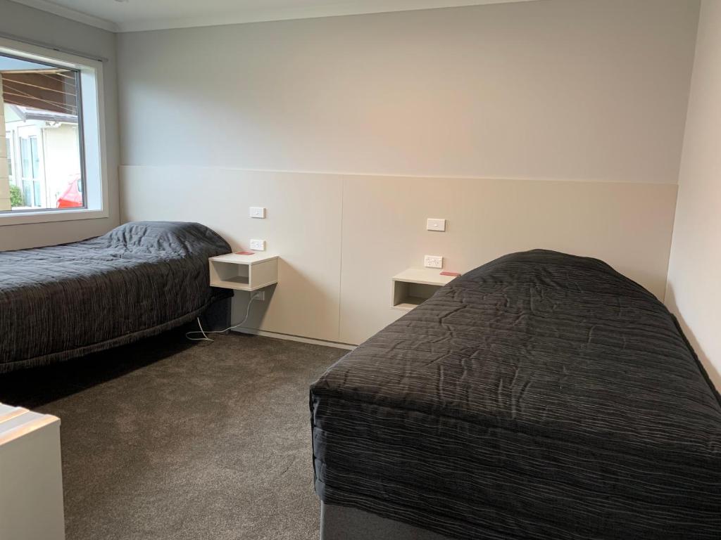 a hotel room with two beds and a window at Kingswood Motel in Waimate
