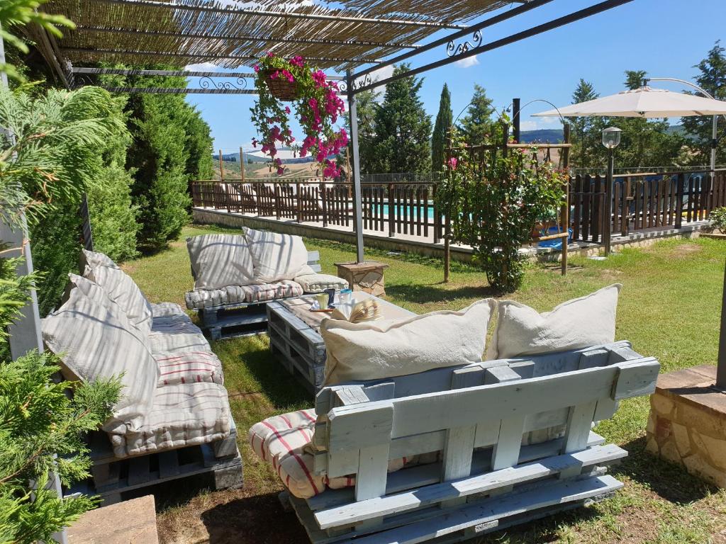 zwei Sofas und Stühle unter einer Pergola im Hof in der Unterkunft Villa with swimming pool - air conditioning - Siena - 10 people - Tuscany crete in Asciano