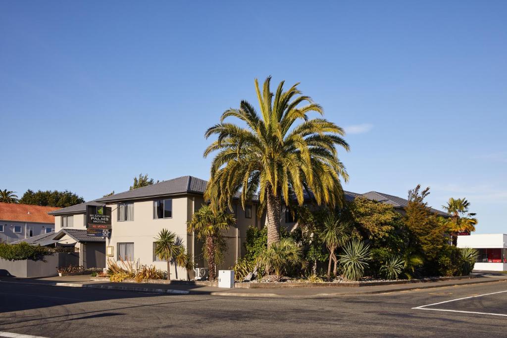 a house with palm trees in front of a street at Blenheim Palms Motel in Blenheim