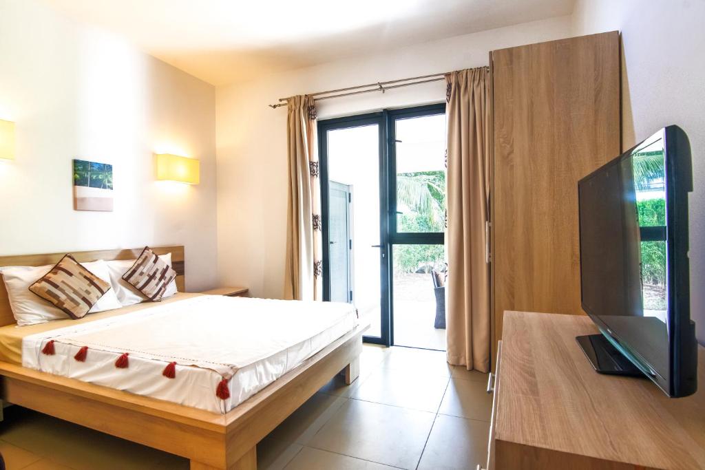 1 dormitorio con 1 cama y TV de pantalla plana en Two Bedroom Apartment with Garden and Pool Access - Azuri Village, Roches Noires, en Roches Noires