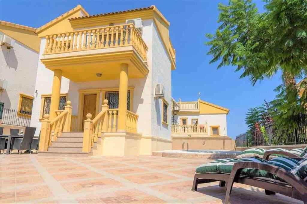 una casa con balcón y un banco frente a ella en Villa Rose - Beautiful detached villa with large private pool, en Villacosta