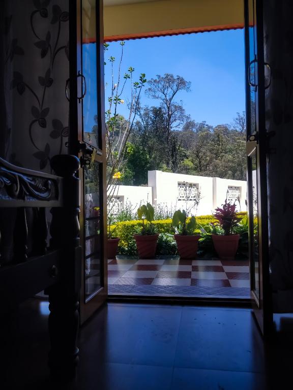an open door to a patio with potted plants at Hidden Heaven in Coonoor