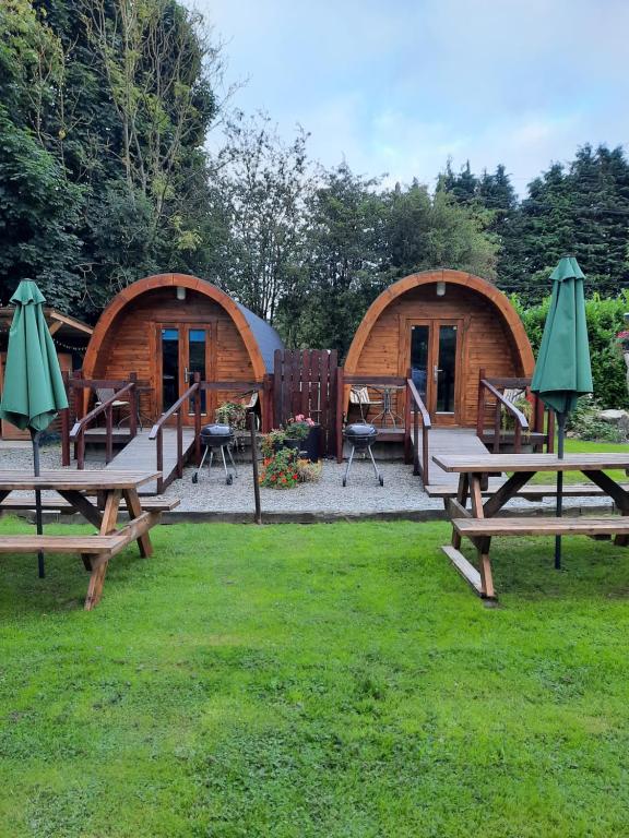 un grupo de mesas de picnic frente a dos cabañas en Log cabin, en Kells