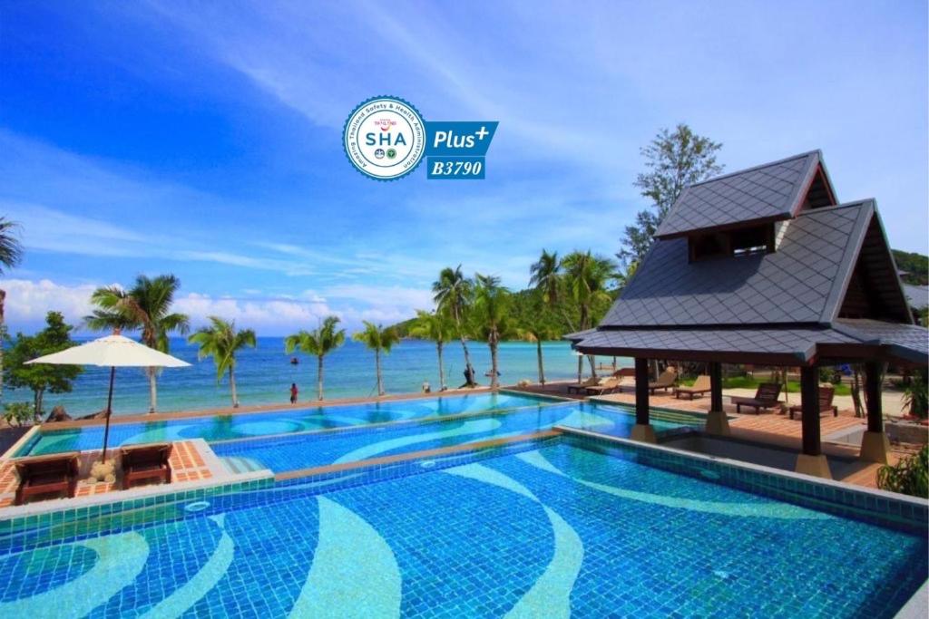 a resort swimming pool with the ocean in the background at Salad Buri Resort- SHA Extra Plus in Salad Beach