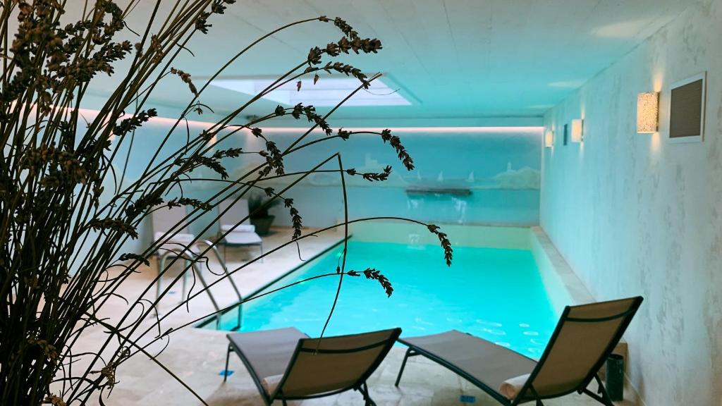 a swimming pool in a house with chairs and a plant at Kaska Ház in Tihany