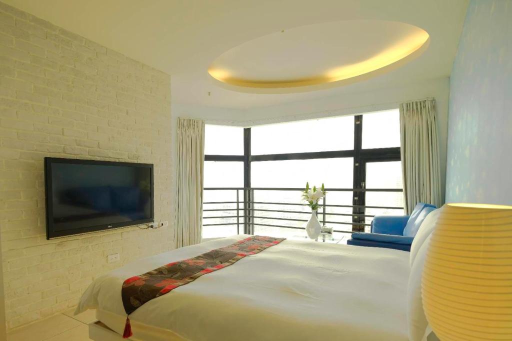 a bedroom with a large bed and a flat screen tv at LJ Hotel in Kaohsiung