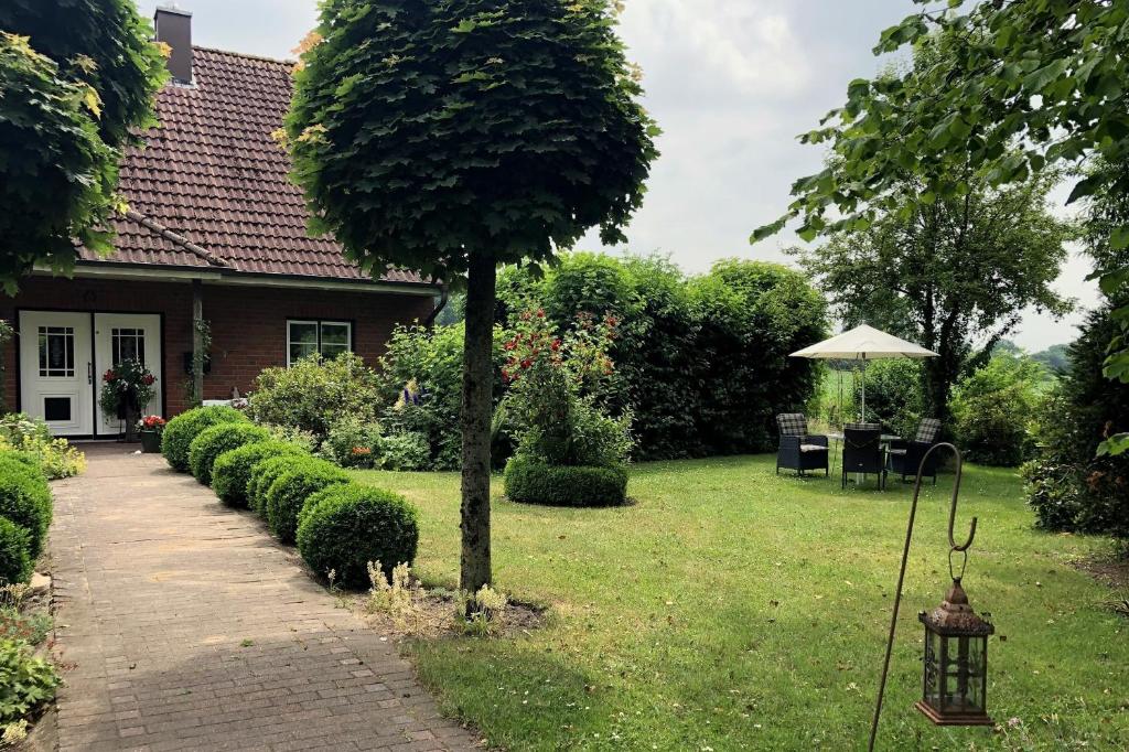 a garden with a tree and a house at Ferienwohnung Rohwer in Jevenstedt