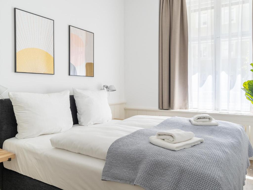 a white bed with two towels on top of it at limehome Berlin Lottumstraße 4 in Berlin