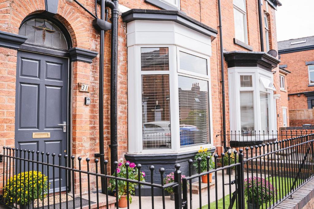 a brick house with a black door and flowers at Home Away From Home in Sheffield