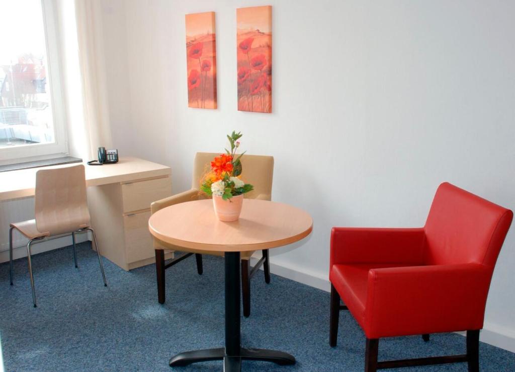 ハーメルンにあるKlein aber fein zentrale Ferienwohnung 30qm im Hotel zur Börseの待合室(テーブル、赤い椅子付)