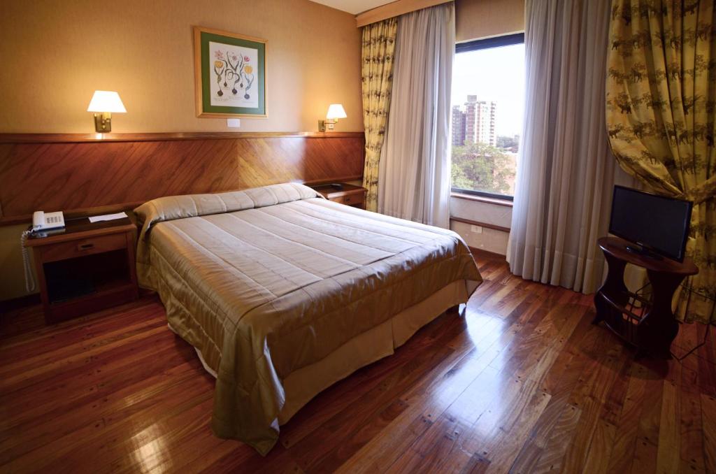 a hotel room with a bed and a window at Premier Hill Suites Hotel in Asunción