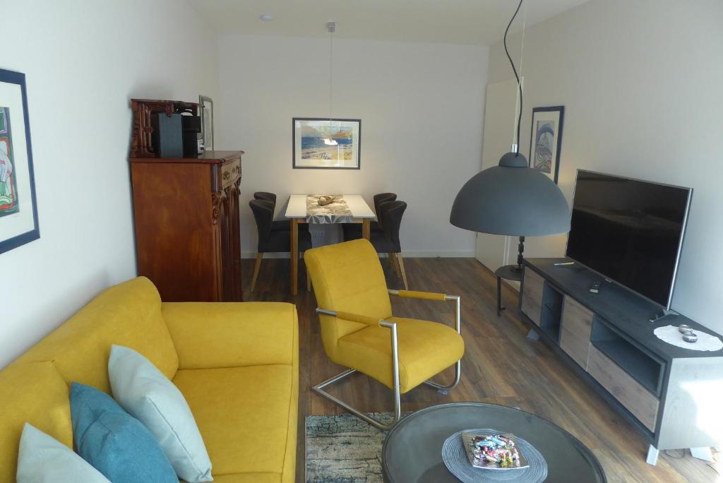 a living room with a yellow couch and a television at Ferienhaus Felix in Heiligenhafen