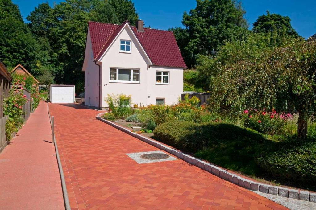 uma casa branca com um telhado vermelho e uma entrada de tijolos vermelhos em Haus Carmesin em Eckernförde