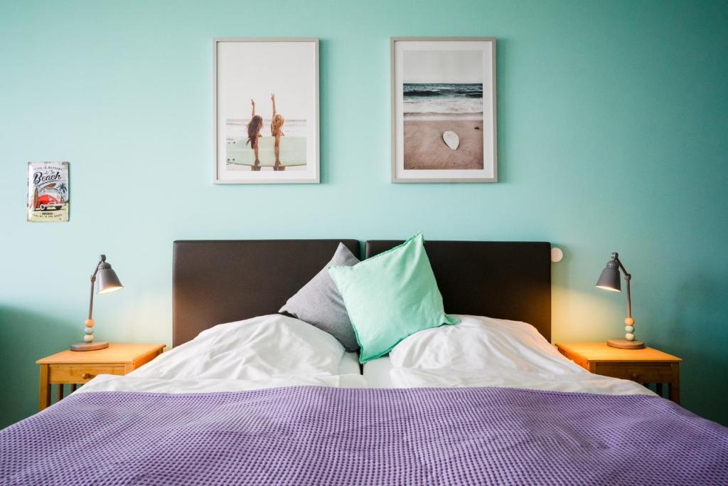 een slaapkamer met een bed en twee foto's aan de muur bij Studio 25 "Surferglück" mit Meerblick in Grömitz