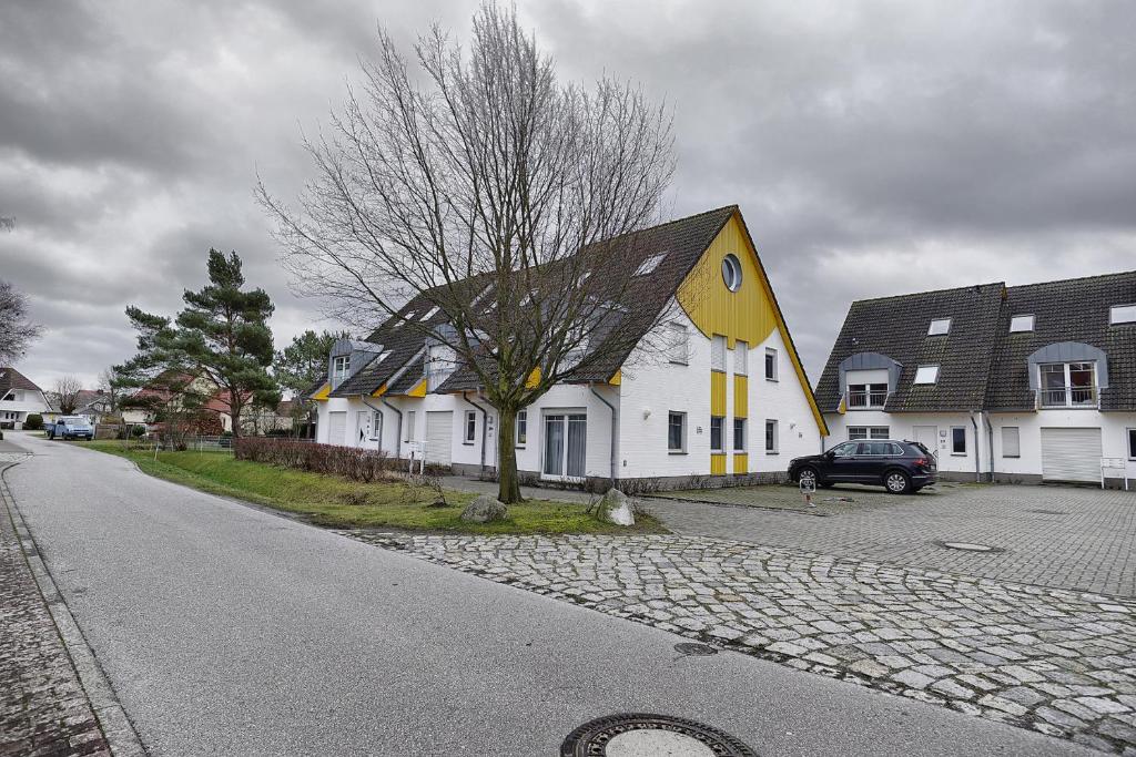 a yellow and white house on the side of a street at Darßer Weg FW 9 in Zingst