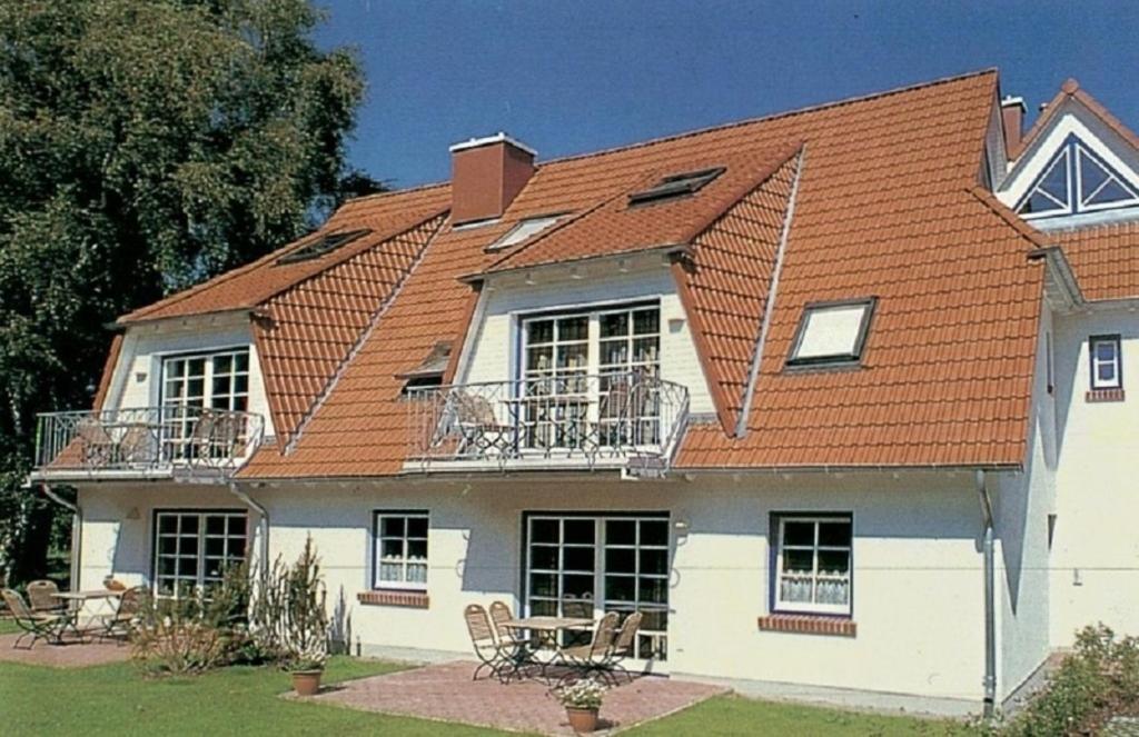 a house with an orange roof with chairs and tables at Haus Weidenhof App 1 in Prerow