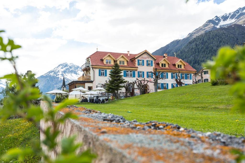 ein Haus auf einem Hügel mit Bergen im Hintergrund in der Unterkunft Meisser Hotel "superior" in Guarda