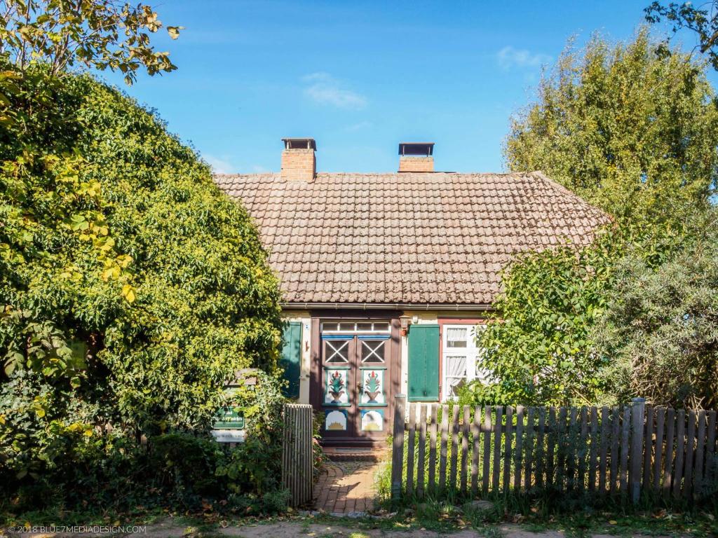プレローにあるaltes Kapitänshäuschenの木塀のある小さな緑の家