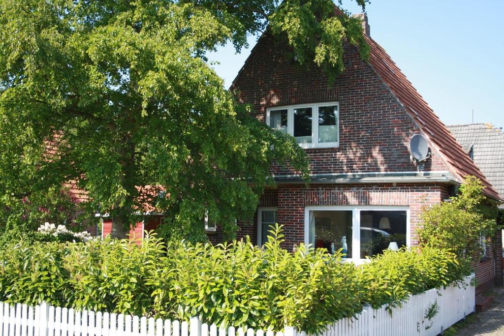 dom z czerwonej cegły z białym płotem w obiekcie Ferienhaus Austernfischer w mieście Butjadingen