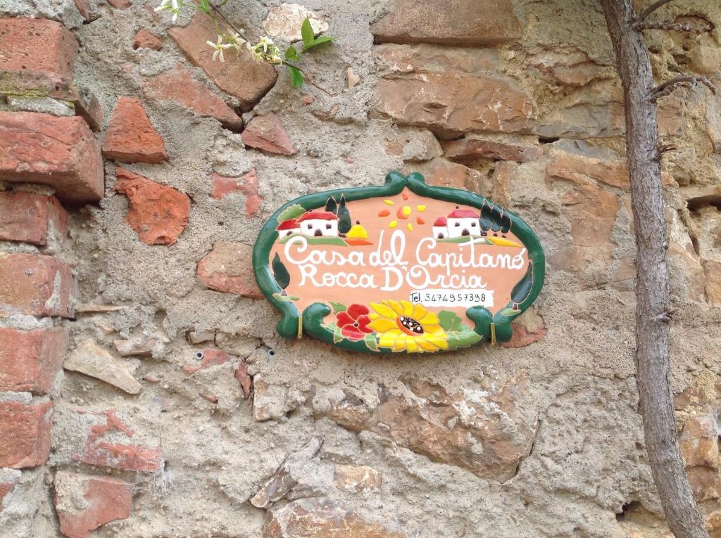 una señal en el costado de una pared de ladrillo en Casa del Capitano Rocca d'Orcia, en Castiglione dʼOrcia