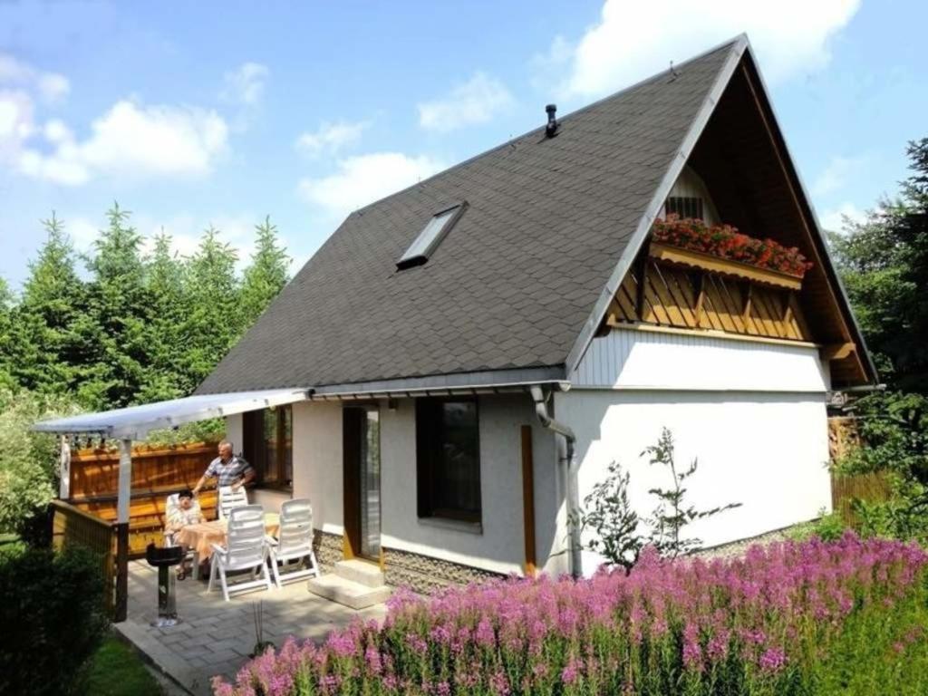 a house with two people sitting on the porch at Ferienhaus Karin in Cranzahl